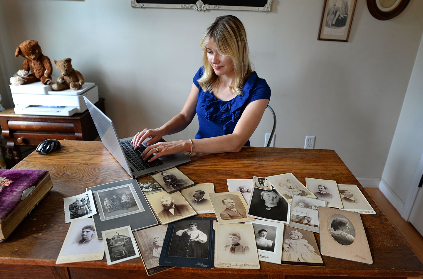 Kate Kelley Typing on Laptop with Photos on the Table